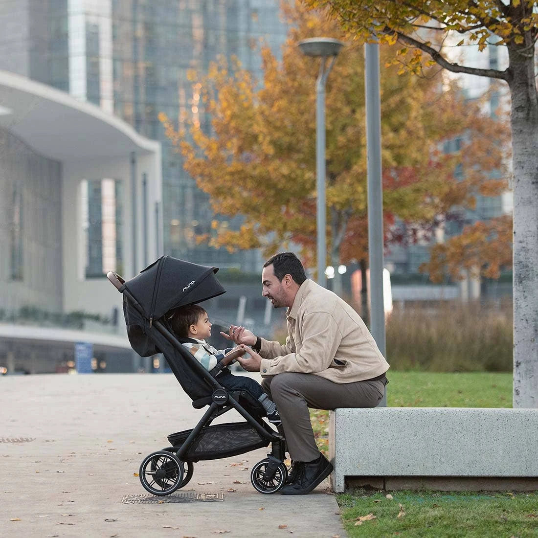 Nuna TRVL LX Stroller + PIPA Urbn Infant Car Seat Travel System showing Nuna TRVL lx Stroller — parent seated beside child in stroller