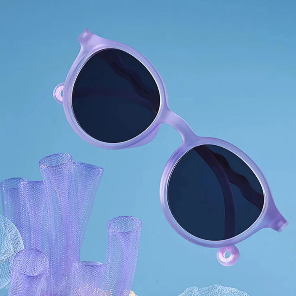 Olivio & Co Oval Sunglasses Junior+ Classic Olivio Shell Purple, purple-framed sunglasses with dark lenses suspended mid-air.