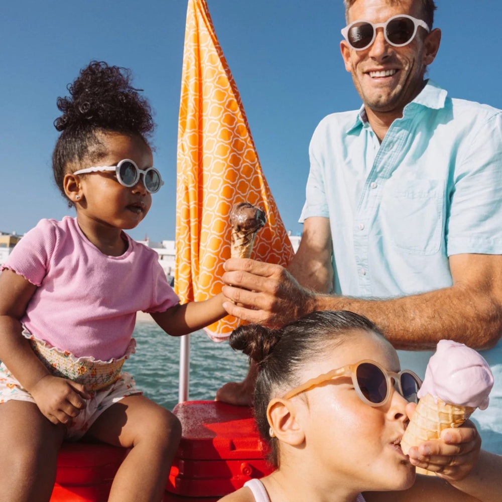 Olivio & Co oval kids sunglasses in white frames; child wearing on sunny boat day