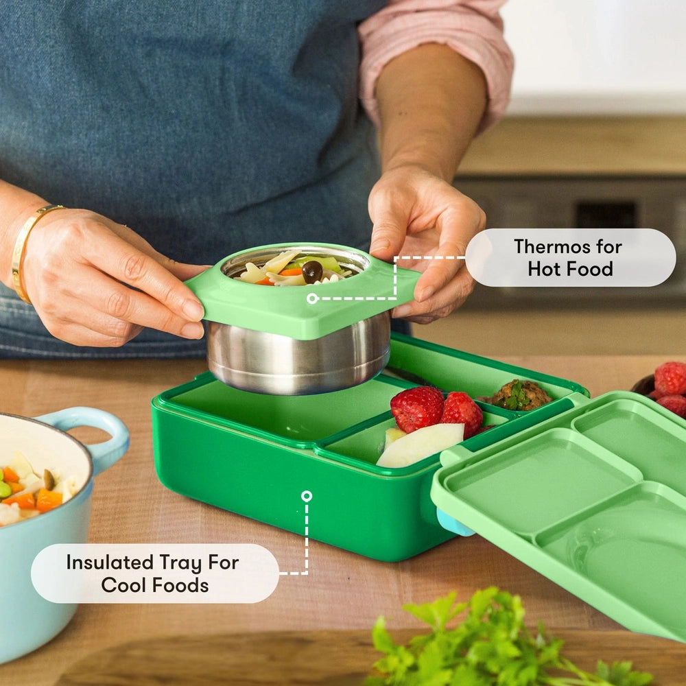 Omiebox Version 2 green lunch box with insulated tray; hands insert the thermos for hot foods.