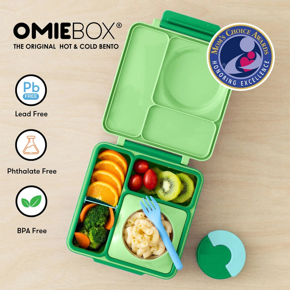 OmieBox Version 2 lunch box in green by Omielife, opened to reveal its divided compartments with fruit and pasta.