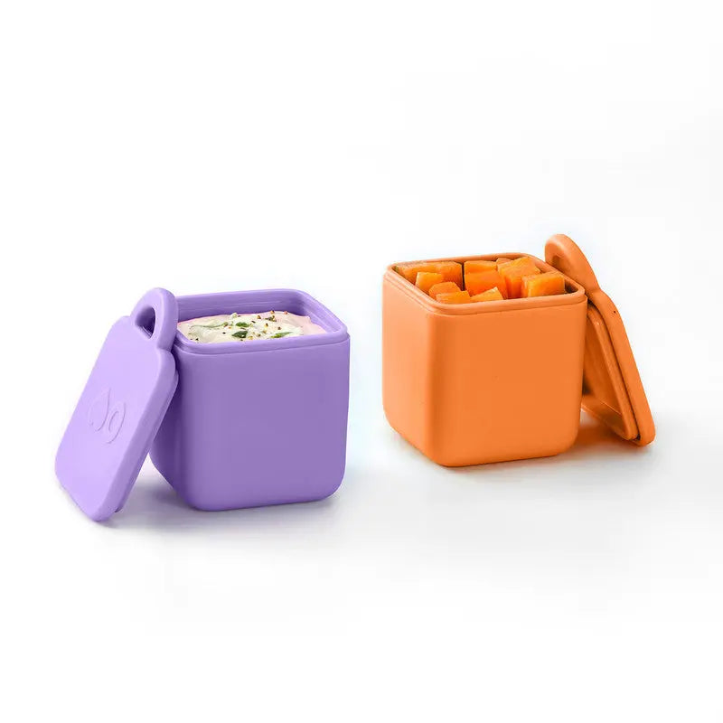Omielife Omiedip Sets: two silicone lunch boxes in purple and orange, lids off showing dip and cubed fruit.