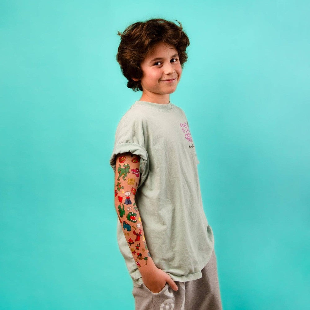 OMY Dinos Tattoos on a boy's arm; colorful dinosaur temporary tattoos visible on his rolled sleeve.