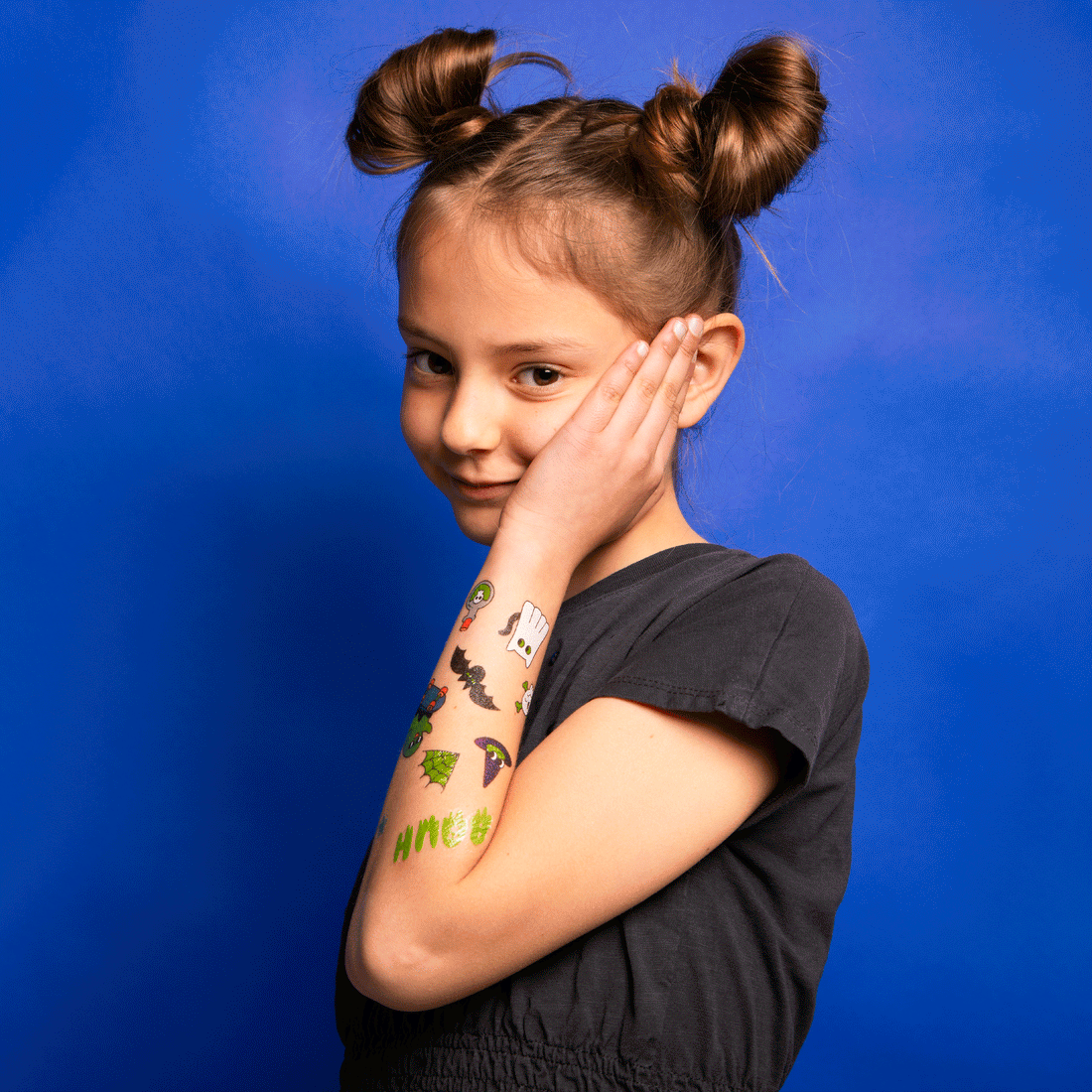 OMY Glow in the Dark Tattoos on a smiling girl, showing colorful designs on her forearm.