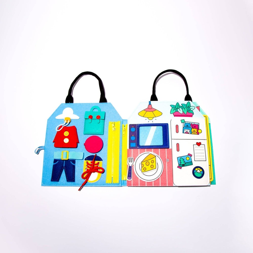 OMY Montessori Play Kit featuring bright felt panels with dress-up and kitchen scenes; child fastens laces and buttons to explore.