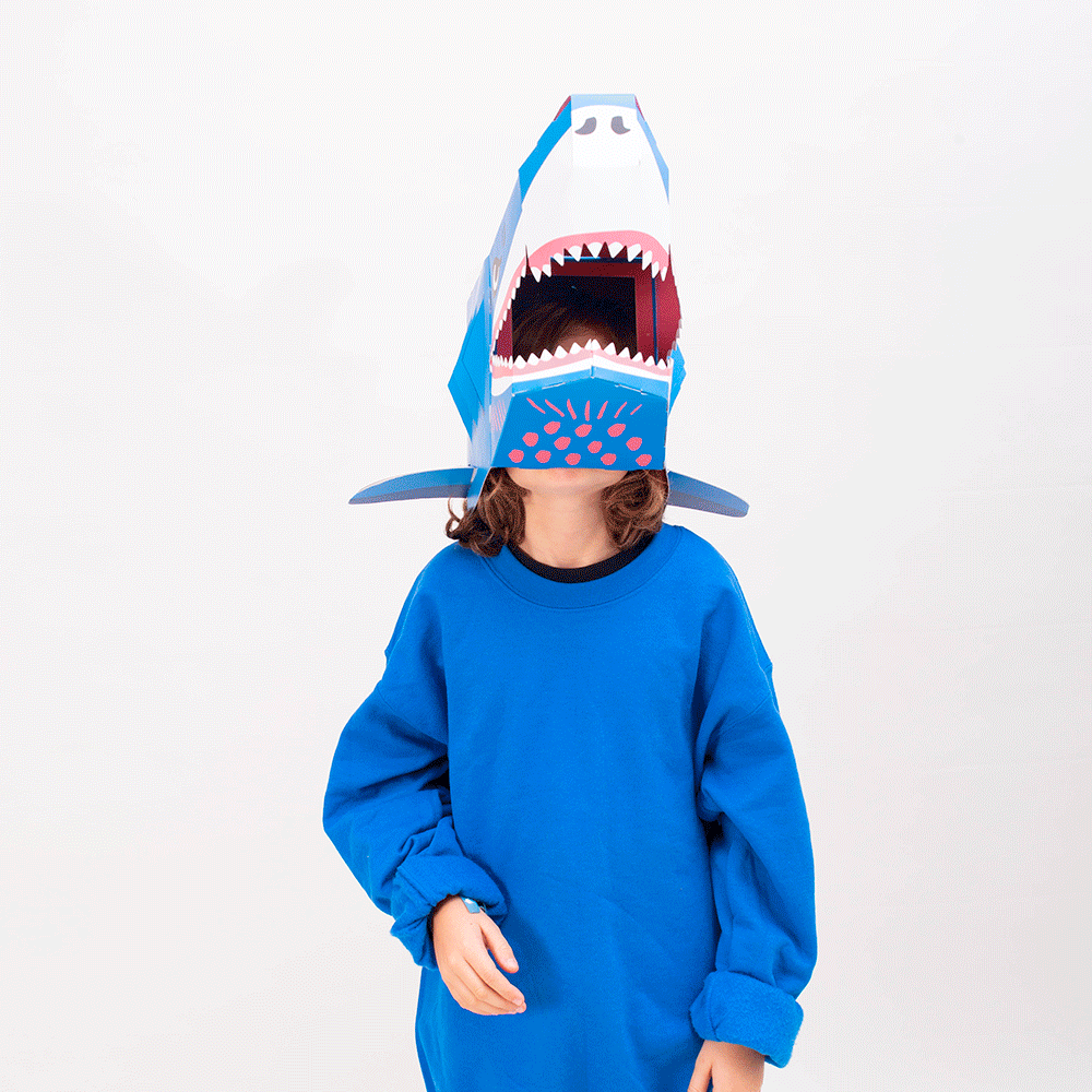 OMY Sharky 3D mask on a child in a blue sweatshirt, jaw-opening shark head helmet with vivid teeth.