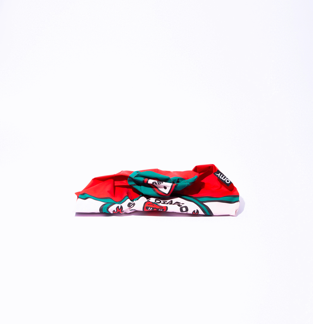 OMY Spicy Diablo giant inflatable pillow, red and teal print, deflated and spread on a white backdrop.