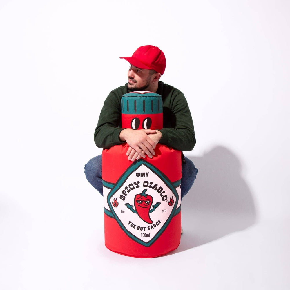 OMY Spicy Diablo Giant inflatable pillow, red with teal cap, hugged by a man to show its oversized playful decor.