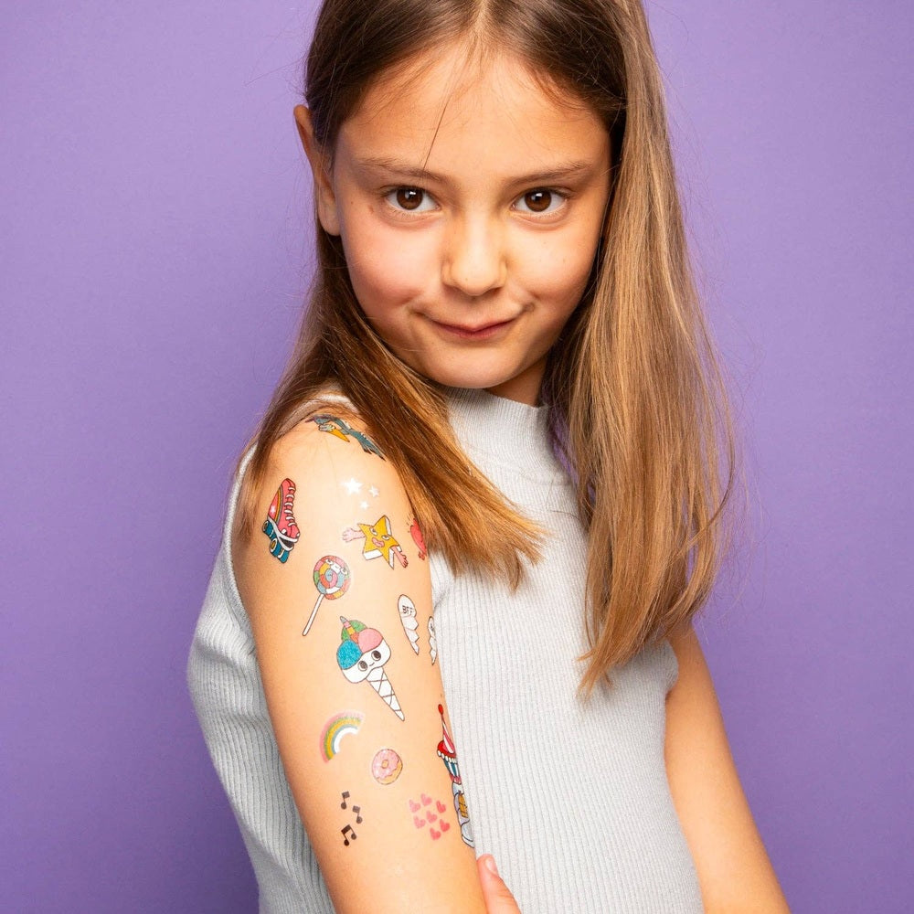 OMY Unicorn Tattoos on a smiling girl's arm with colorful unicorn and rainbow stickers from a temporary tattoo set.