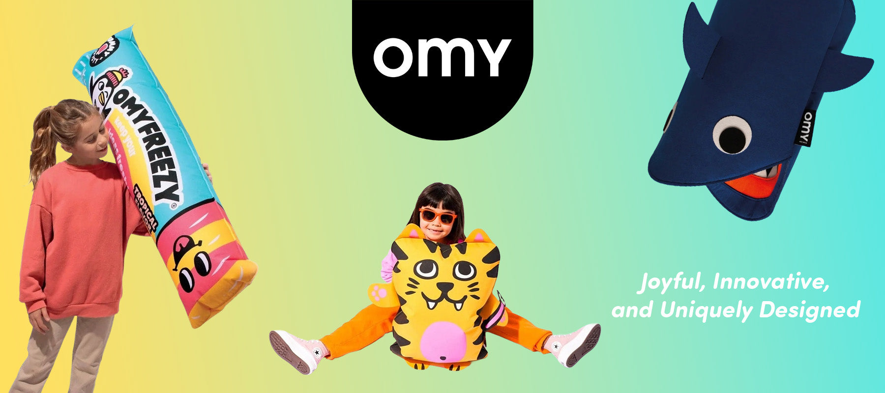 OMY horizontal banner showing kids with a giant Omyfreezy plush and tiger backpack at baby enRoute.
