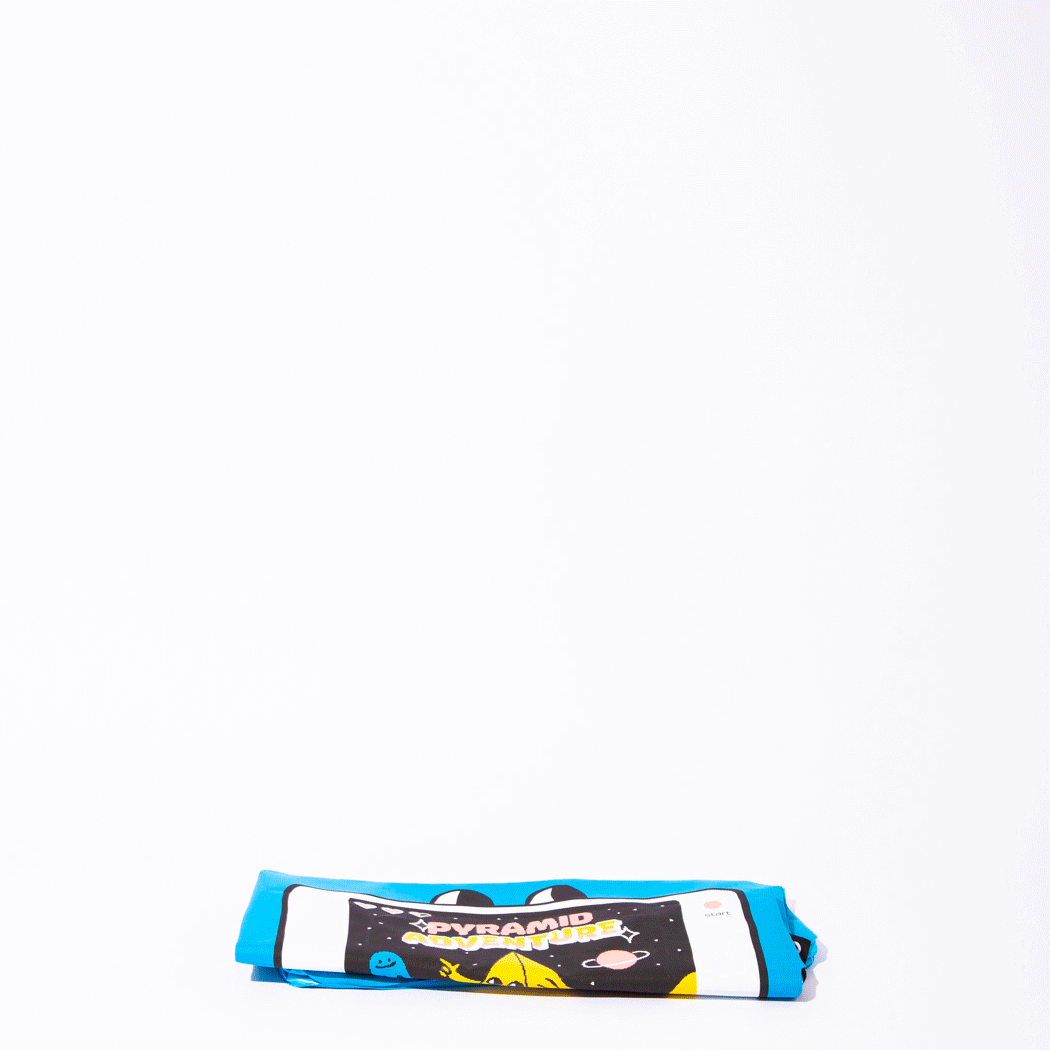 OMY Giant inflatable pillow in blue with colorful video game art, rolled up for easy use.
