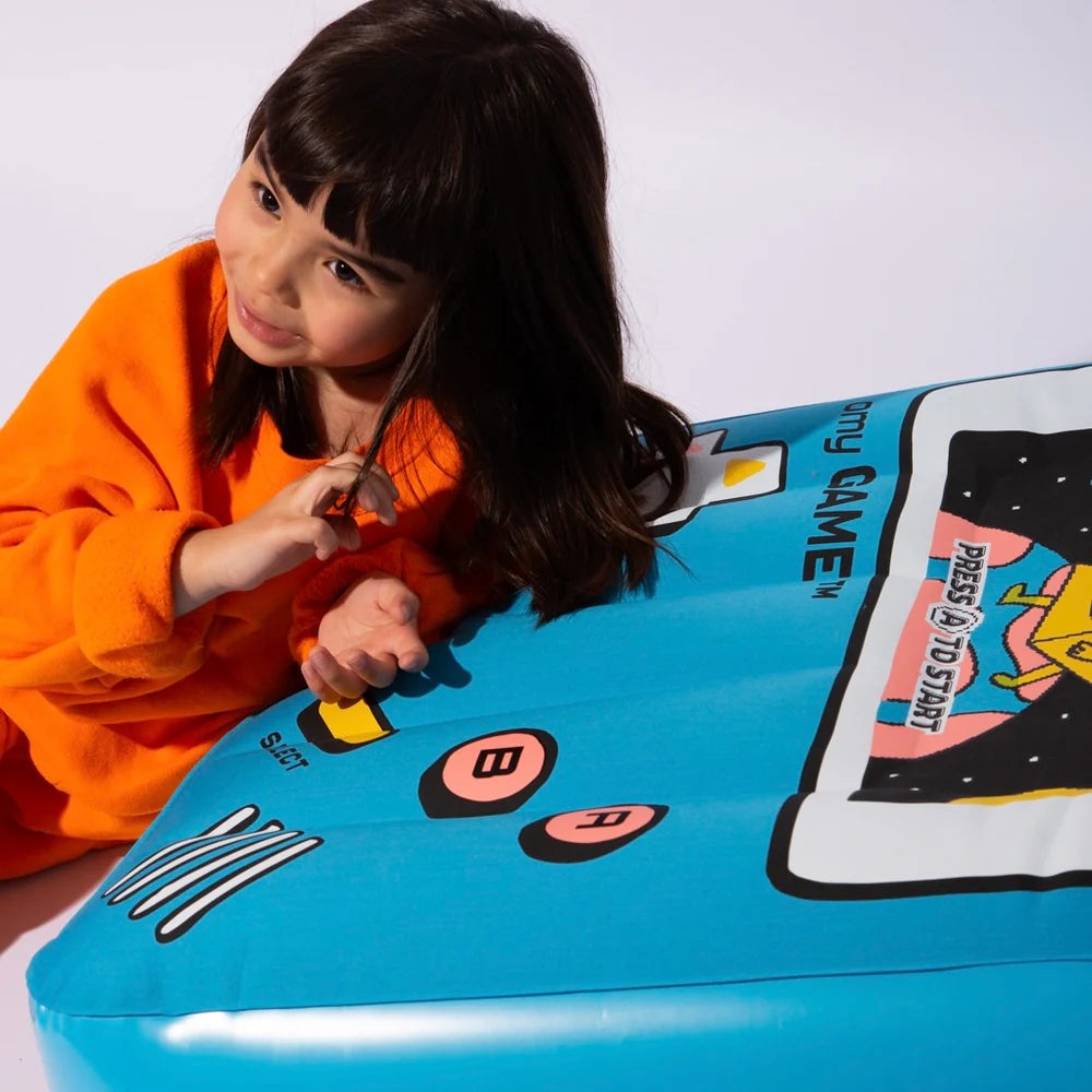 OMY Giant inflatable pillow - Video game; bright blue with game graphics, child leaning on its soft surface.
