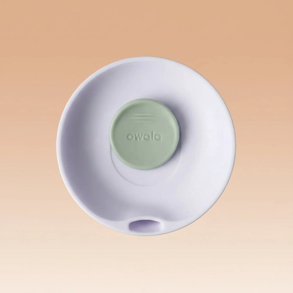 White electronic device with a green button labeled 'owala' on a white background