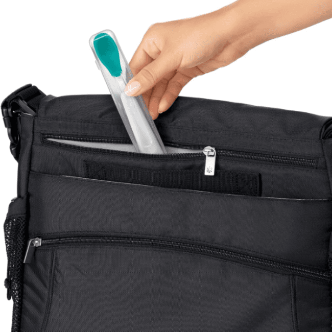 OXO Tot Travel Feeding Spoon Teal being tucked into a black bag pocket for on-the-go feeding