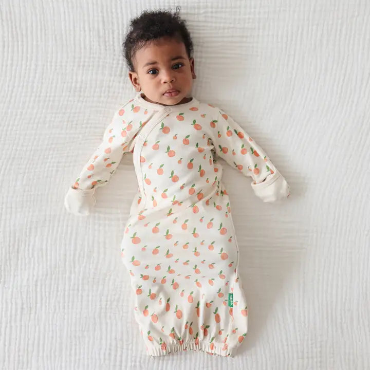 PARADE Organic Gowns Signature Prints baby gown, white with peach prints, soft organic fabric; baby lying calmly on a white blanket.
