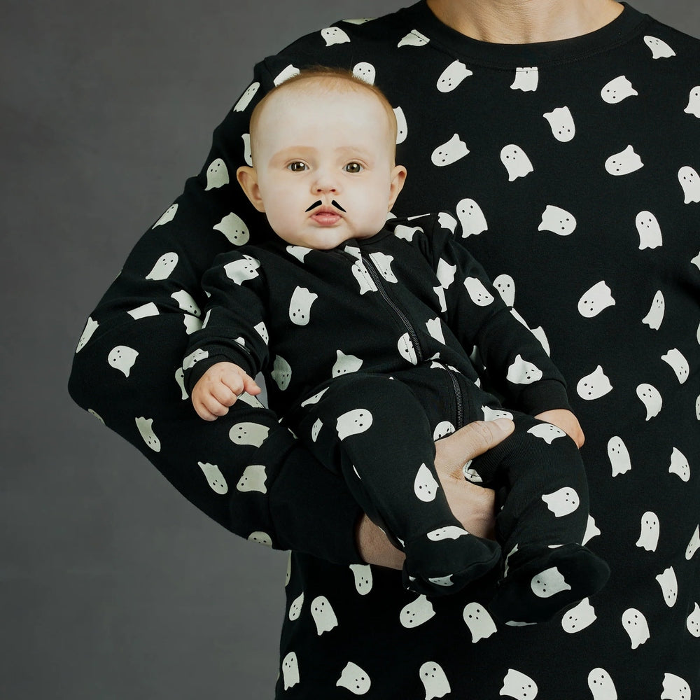 Petit Lem Ghosts Glow In The Dark Print On Black Sleeper, a black zip-front baby onesie with white ghost motifs.
