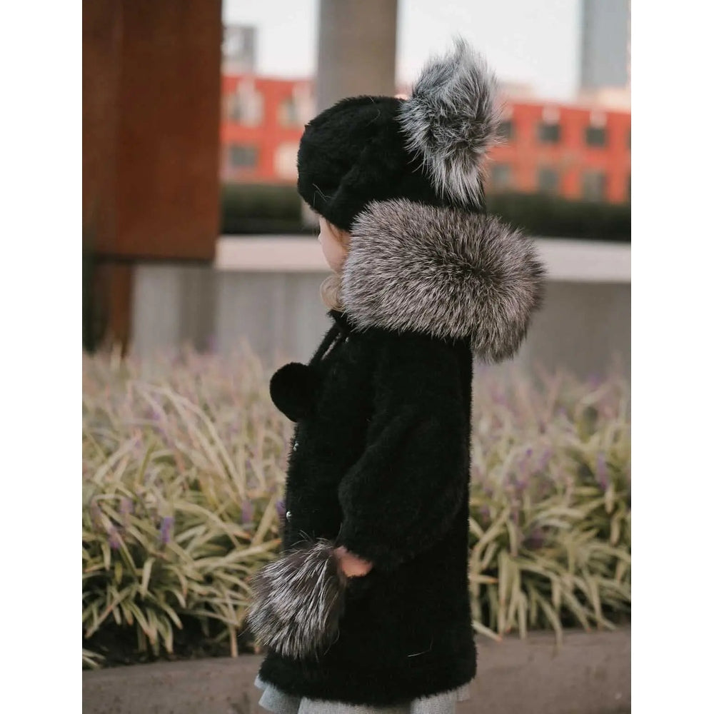 Petite Maison Kids Milana Noir sweater coat in black knit with gray faux fur trim on hood, worn by toddler outdoors