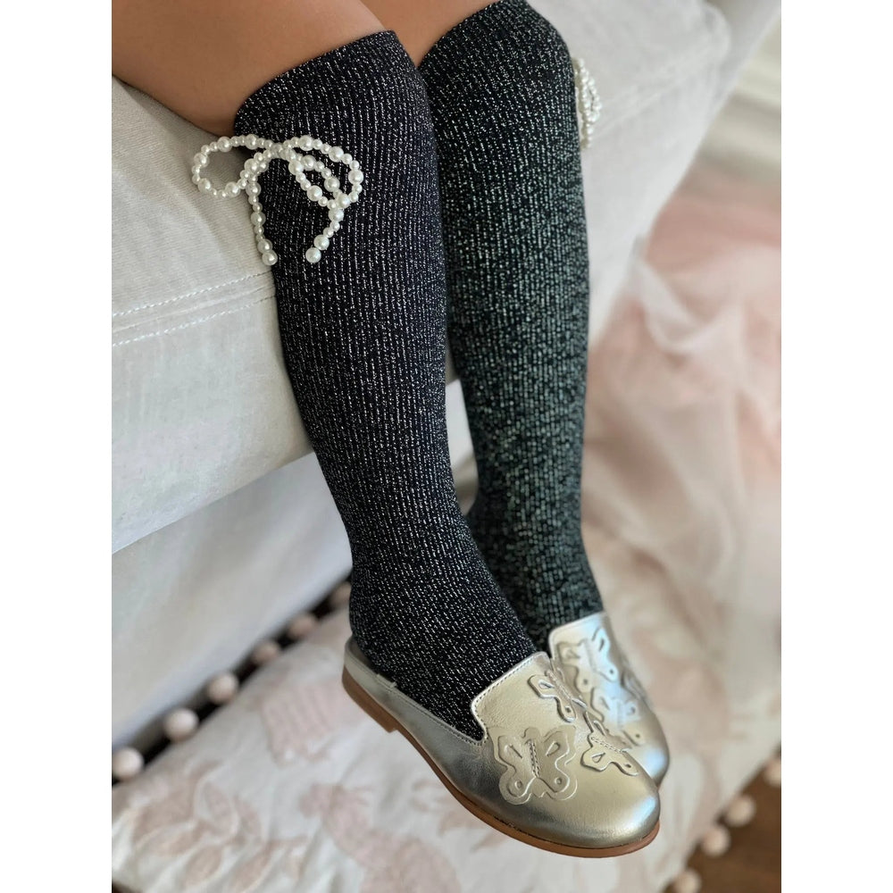 Petite Maison Kids Perla Shimmer Socks knee-high black glitter with pearl bow, worn on a child's legs.