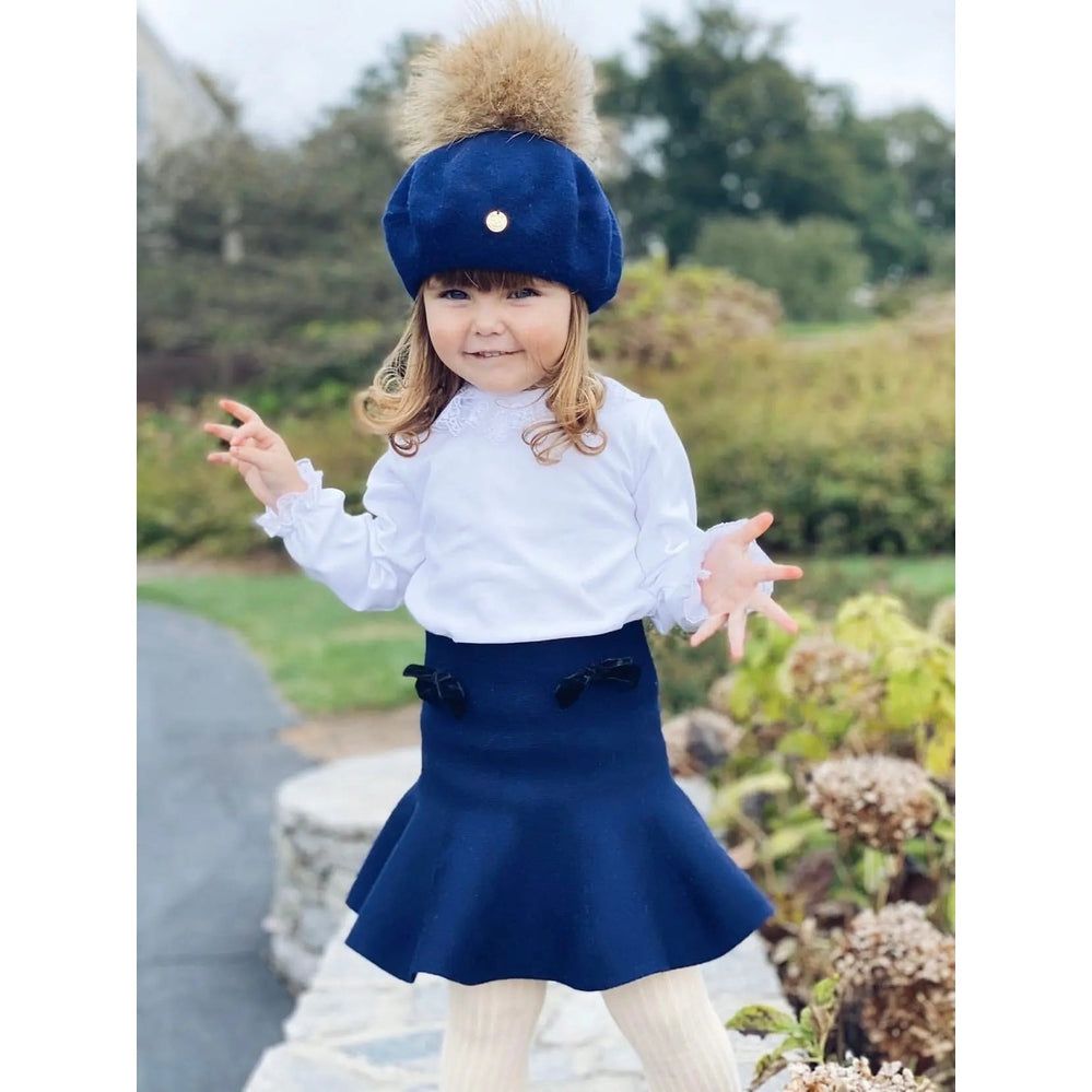 Petit Maison Kids Wool Beret With Pom Pom, navy blue with fluffy pom, on a smiling toddler outdoors