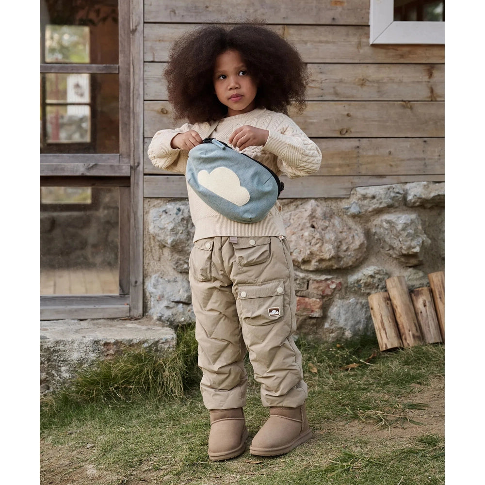 Petite Revery Corduroy Bumbag Dusk Blue carried by a child outdoors, cloud patch visible as she opens the zipper.