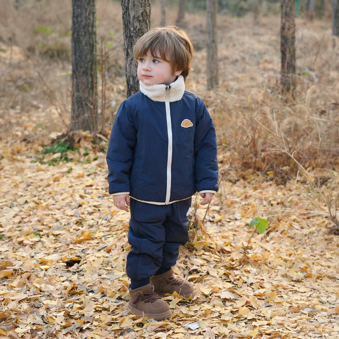 Petite Revery Cozy Crumbs Reversible Fleece Jacket in Blueberry, child wearing the navy side outdoors