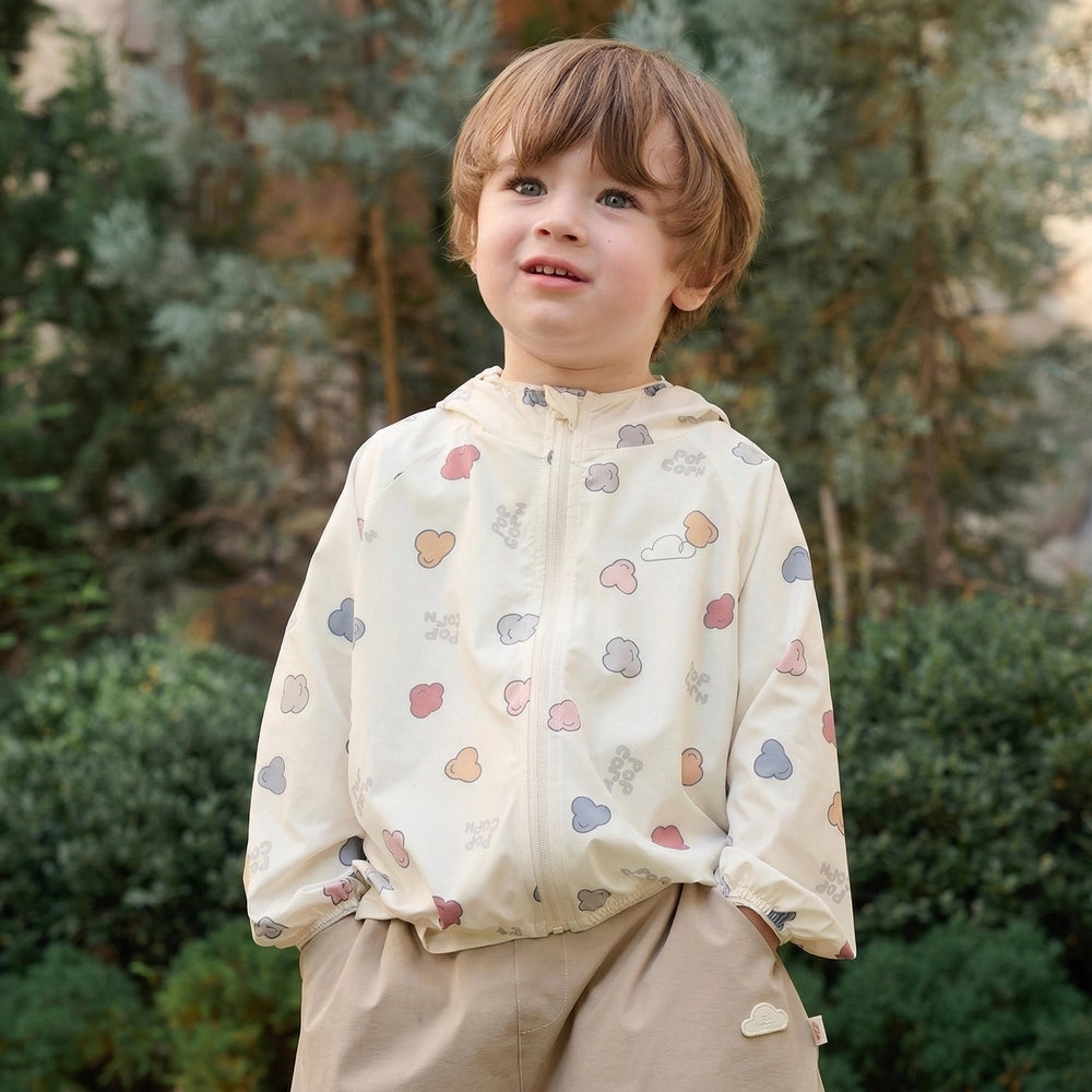 Child wearing a light-colored jacket with cloud patterns outdoors