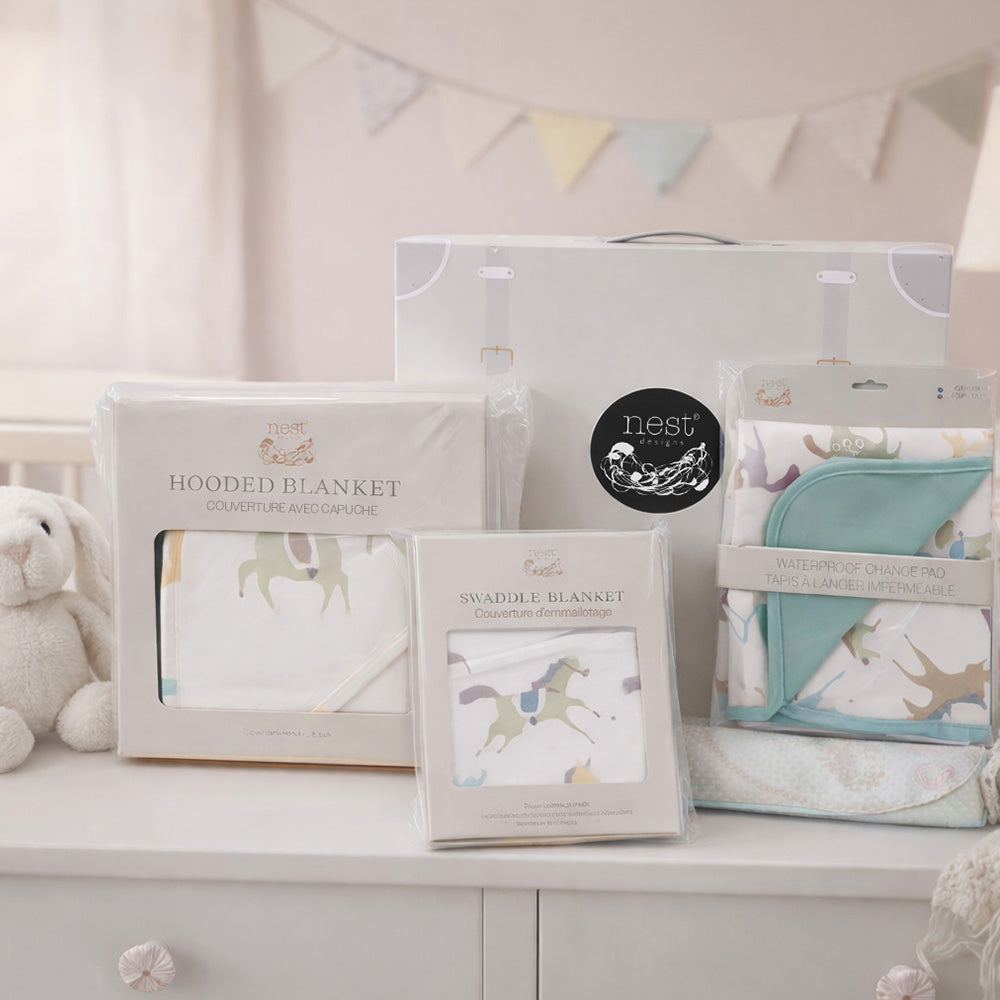 Baby blankets in packaging on a white surface with a baby-themed decoration in the background