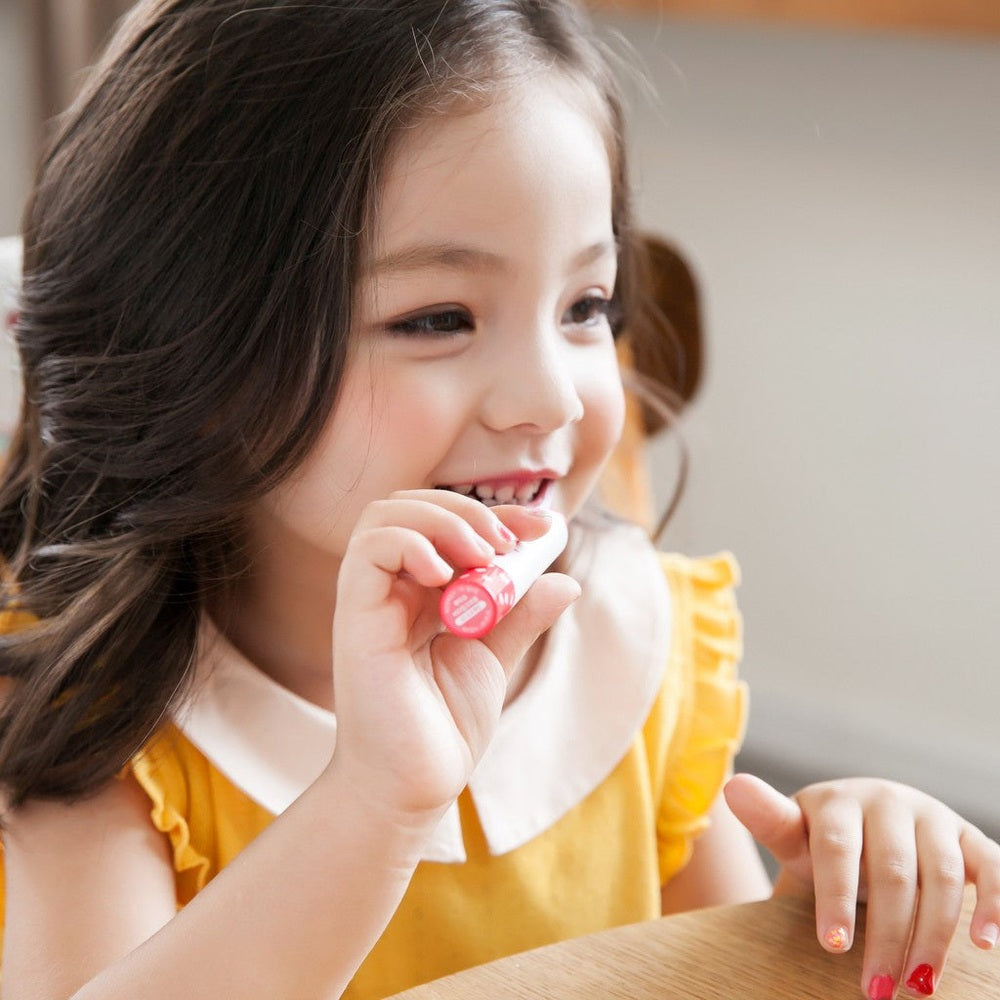 PUTTISU Butter Lip Crayon #02 Blossom Pink on a smiling child, pink lip color