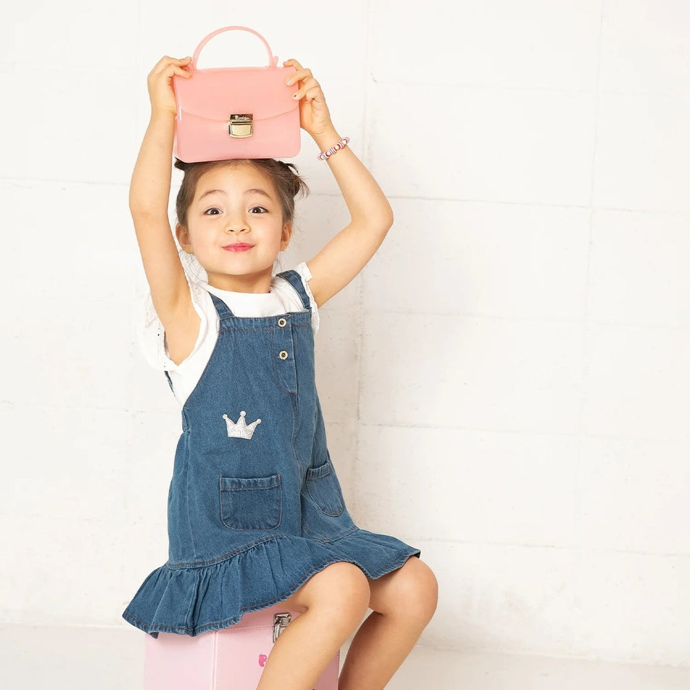 Puttisu Charming Bag pink faux leather handbag held aloft by smiling girl