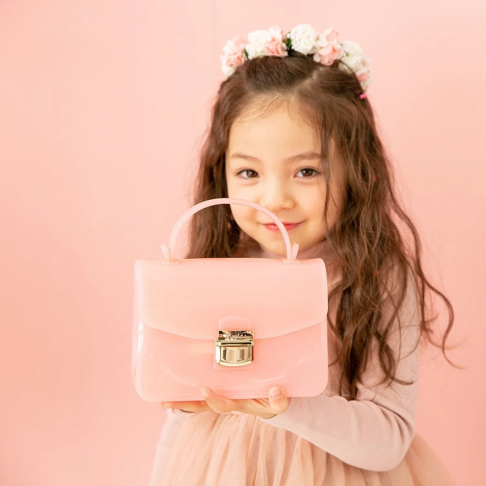Puttisu Charming pink handbag with gold lock, held by a smiling girl in a flower crown.
