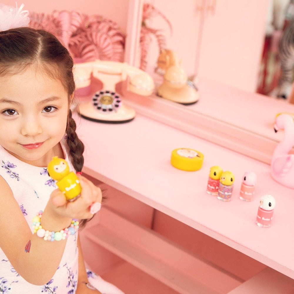 PUTTISU Pangpang Nail Art Kit Pink Snow; pastel nail polishes on a pink vanity with a young girl showing one