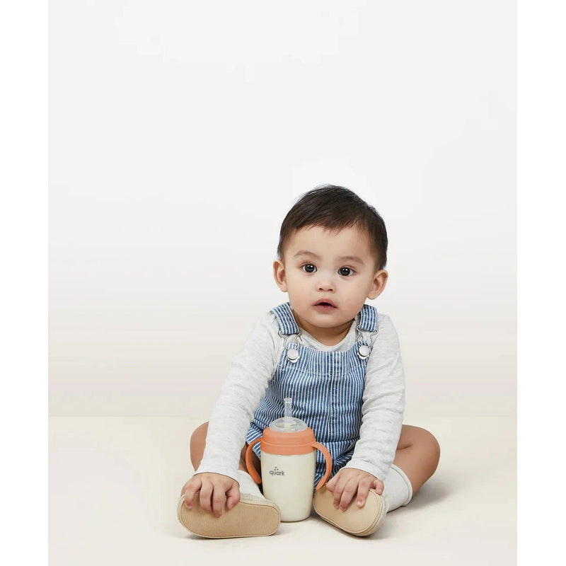 Quark Buubibottle Sipkit Training Cup Conversion Kit with peach lid and side handles, held by a seated baby.