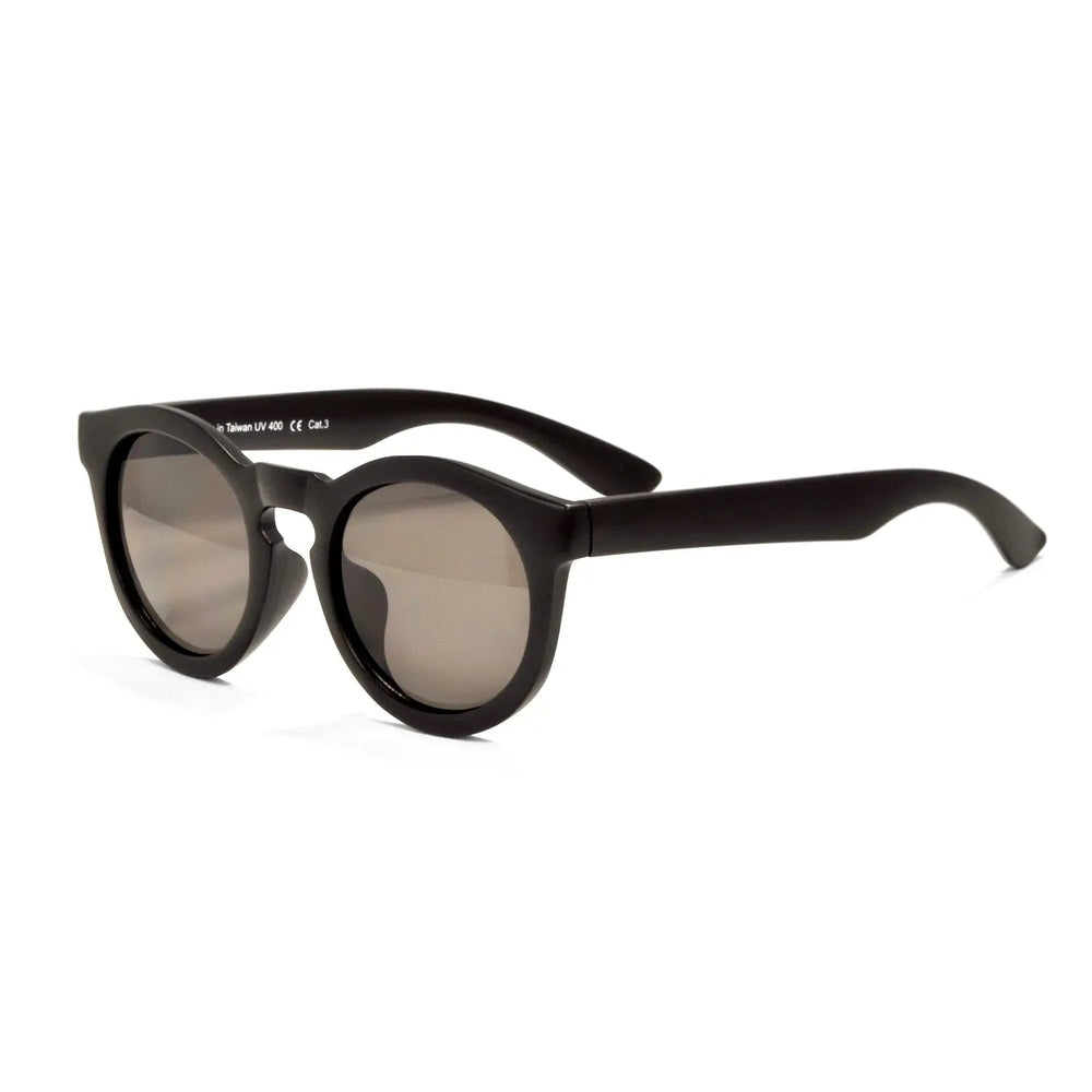 Real Shades Chill Sunglasses Kids Black with brown lenses resting on a white surface.