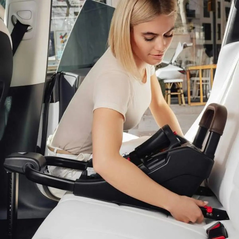 Romer Juni Infant Car Seat with Versa Base in a car, a woman fastening the base to the seat.