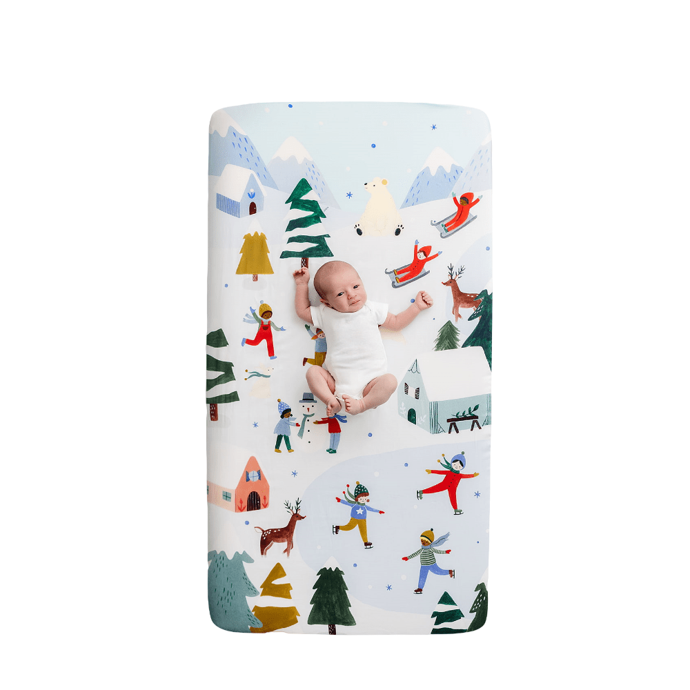 Rookie Humans cotton sateen crib sheet Snowy Day with winter village scene and pine trees