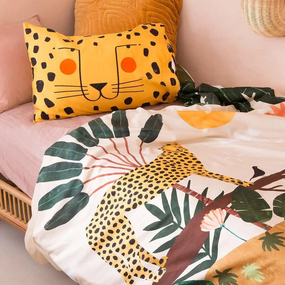 Rookie Humans Kids Bedding Set In The Jungle on a cozy bed with a yellow leopard face pillow and tropical leaf duvet.