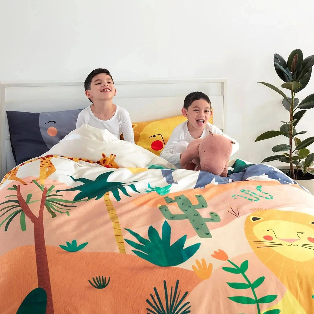 Rookie Humans Kids Bedding Set In The Savanna with bright savanna animals, two kids tucked under the colorful duvet.