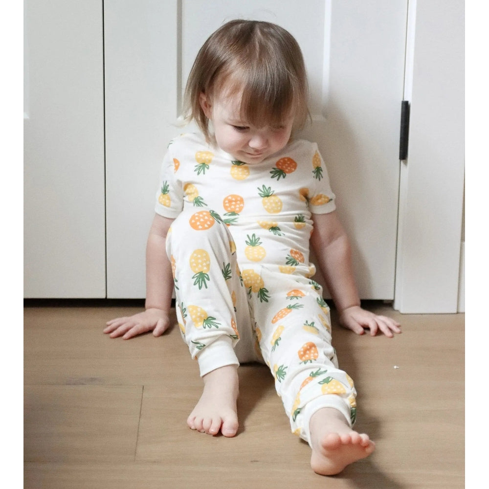 Silkberry Baby Bamboo Short Sleeve 2 Pc Pajama Set Pineapple Love: toddler in white pineapple-print PJs sits on hardwood floor