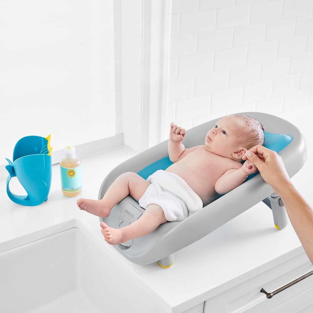 Skip Hop Moby Recline and Rinse Bather with gray tub and blue headrest; baby in bath on counter