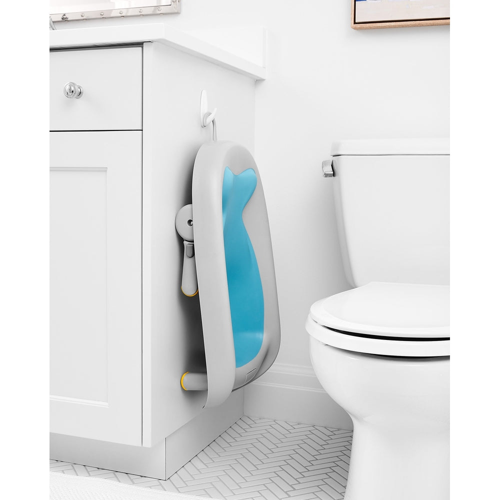 Skip Hop Moby Recline and Rinse Bather in gray frame with blue insert mounted on a bathroom cabinet.
