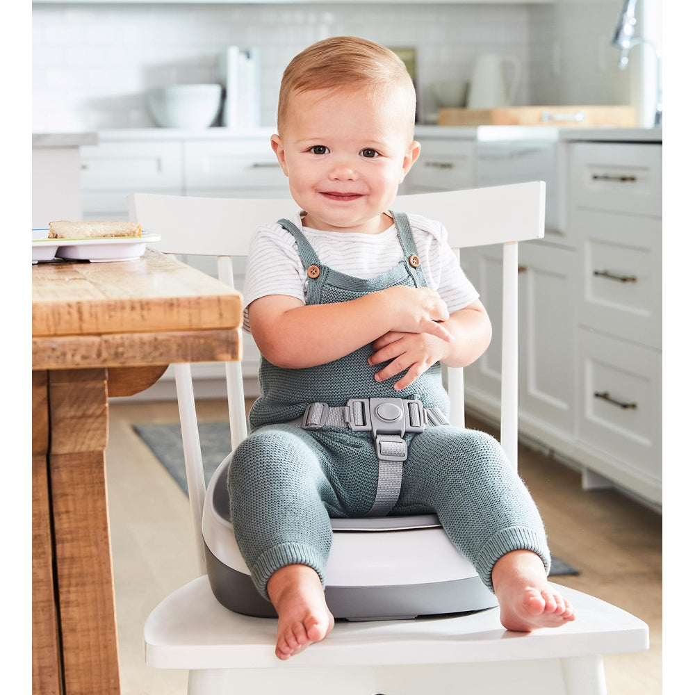 Skip Hop Sleek Seat Booster in grey/white with child seated at dining table