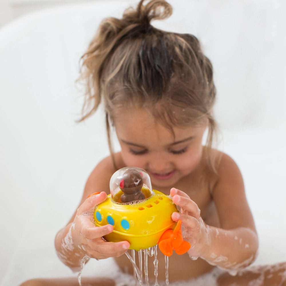 Skip Hop Zoo Pull & Go Submarine bath toy in yellow with blue portholes and orange propeller, held by a child