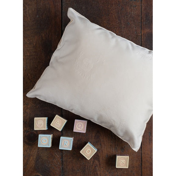 Sleeptek organic shredded-rubber baby pillow in white fabric with seven pastel alphabet blocks nearby