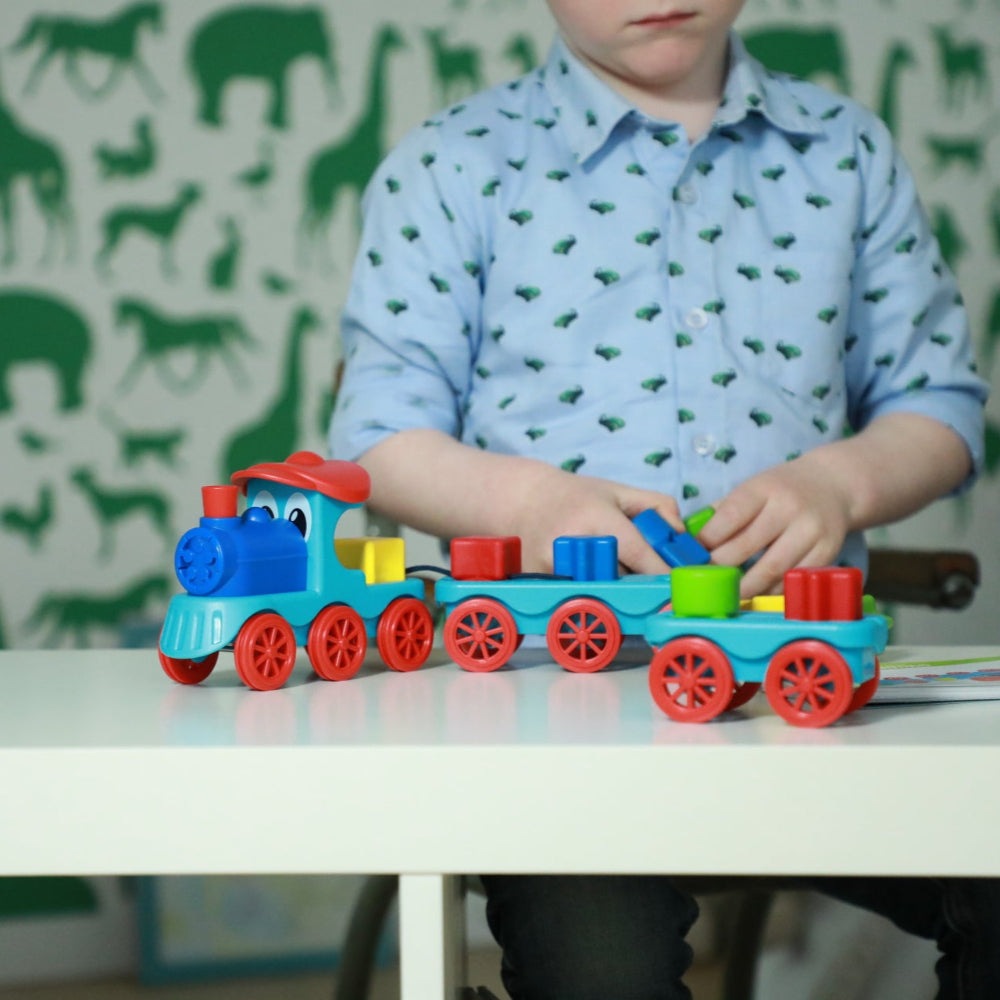 Smart Games Brain Train toy train set with colorful blocks and blue and red cars; child playing