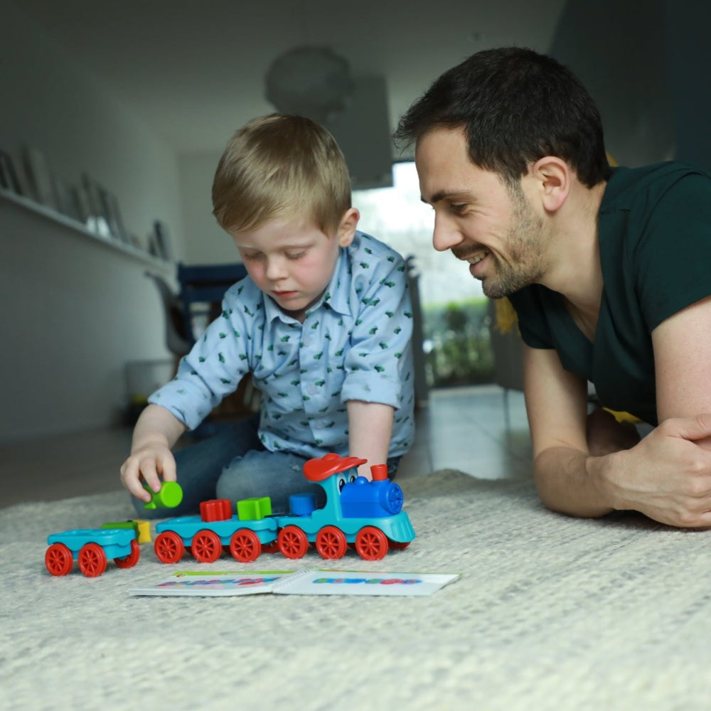Smart Games Brain Train educational toy train set with colorful blocks, being played by a child and adult