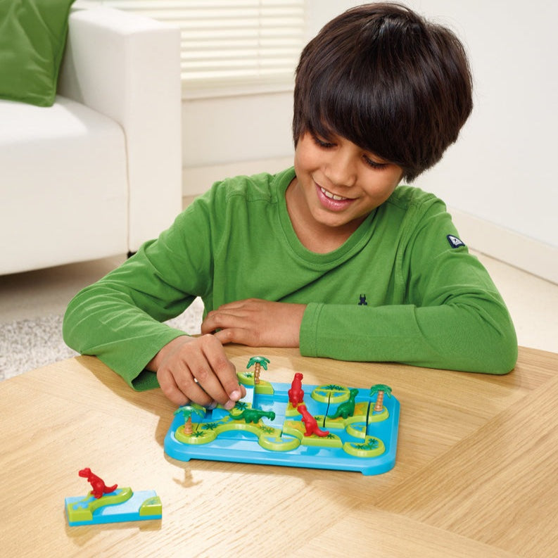 SMART GAMES Dinosaurs Mystic Islands puzzle on blue island board with colorful dinosaur pieces; child playing.
