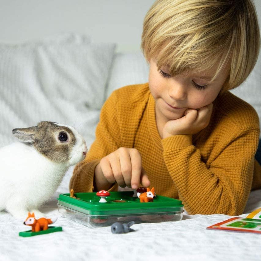 Smart Games Jump In puzzle game on green base with two fox figurines; child in mustard sweater playing.
