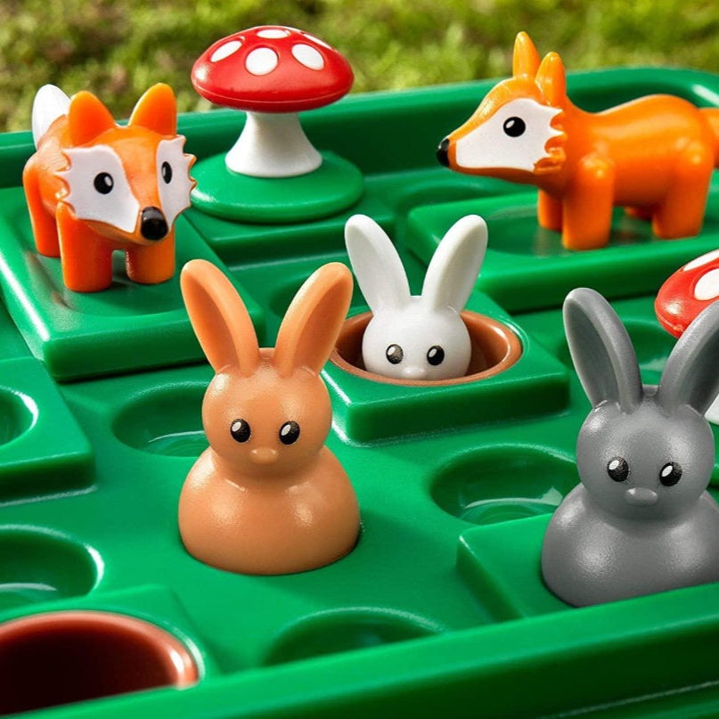 Smart Games Jump In game pieces: five animal figures (bunnies and foxes) on a green maze board with red mushrooms