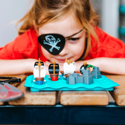 Smart Games Pirates Crossfire puzzle game with five pirate ships on a bright blue, wavy board.