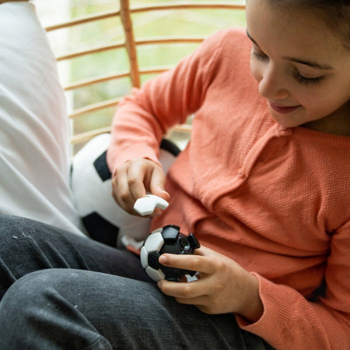Smart Games Plug & Play Ball educational toy; child playing with black and white hex-puzzle ball.